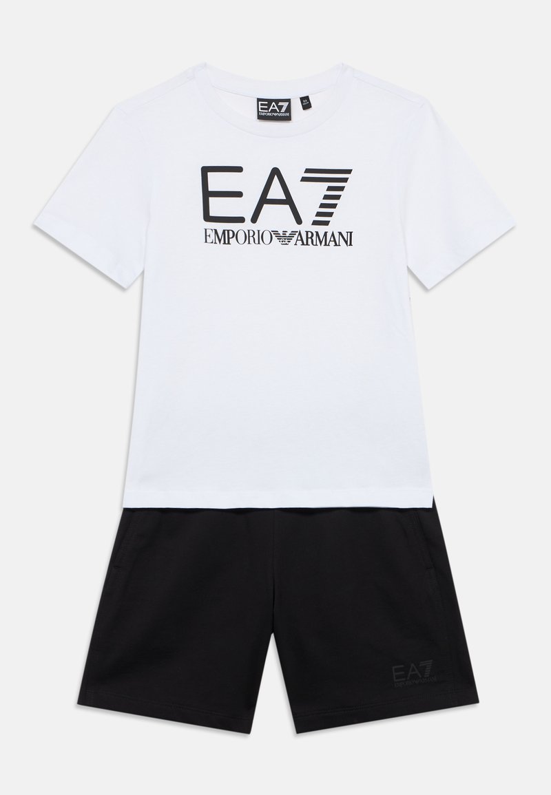 Valge puuvillane T-särk musta "EA7 Emporio Armani" logoga, millel on mustad lühikesed püksid, mille ääre lähedal on väike logotrükk.