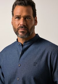 Blauwe wangpatroon knoopshirt met staande kraag, met een klein geborduurd logo op de borst en een gestructureerde stof.
