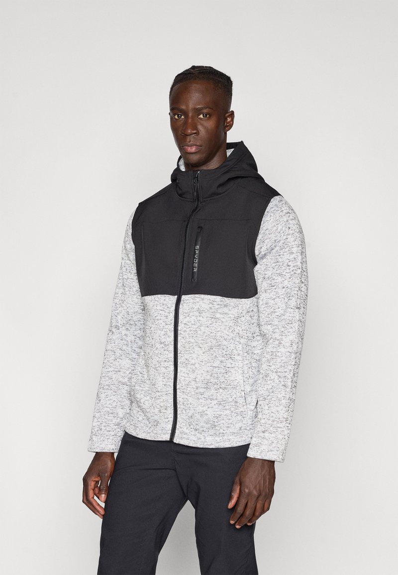 Veste à capuche avec une partie supérieure noire et une partie inférieure gris clair mouchetée. Fermeture éclair à l'avant, tissu texturé et poches latérales.