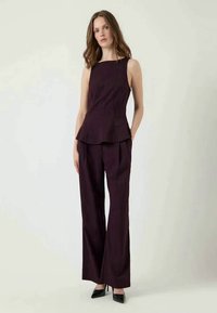 Burgundská dvojdielna súprava obsahujúca bezrukávový peplum top a široké nohavice, vyrobená z textúrovanej tkaniny, doplnená čiernymi opätkami.