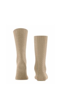Calzini lavorati a maglia beige con un motivo testurizzato, caratterizzati da un risvolto a coste e una soletta liscia. Sono alla caviglia e realizzati in materiale morbido.