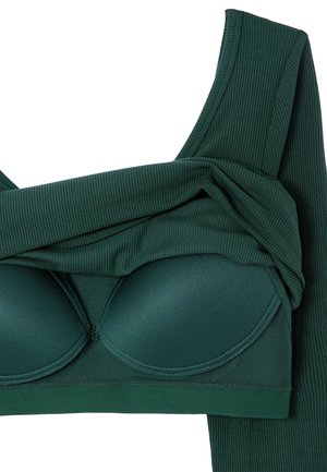 Dunkelgrünes, geripptes Oberteil aus Stoff mit herausnehmbaren Polster-Cups und breiten Trägern, gefaltet, um die Innenstruktur und Textur zu zeigen.