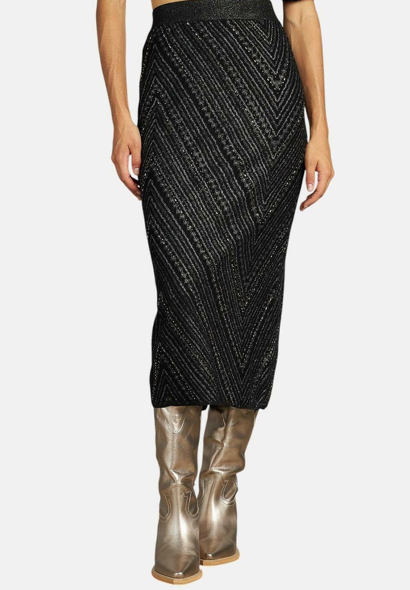 Jupe en tricot noire avec un motif en zigzag, featuring des fils métalliques. Associée à des bottes dorées brillantes jusqu'au genou. Silhouette évasée.