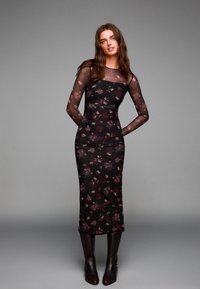 Čierne šaty s dlhými rukávmi a kvetinovou potla�čou v burgundskej a fialovej farbe. Priesvitné sieťované rukávy, priliehavý korzet a rovný maxi strih. Nosené s čižmami po kolená.