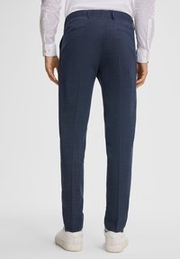 Pantaloni blu navy con un motivo testurizzato, design slim fit, due tasche posteriori, indossati con sneakers bianche.