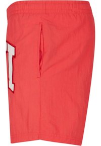 Red shorts made of lightweight fabric, featuring a side pocket and a large white letter "I" embroidered on the front.