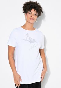 Bílý krátký rukáv T-shirt s květinovým vzorem vytvořeným ze stříbrných kamínků na přední straně. Tkanina má hladkou texturu a volný střih.