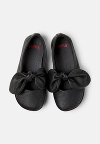 Zapatos de cuero negros con punta redondeada y un gran lazo de nudos en la parte frontal. Superficie texturizada con diseño sin costuras.