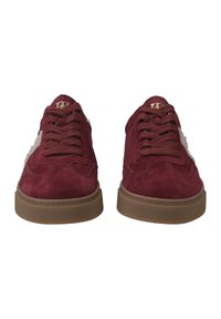 Sneaker in suede bordeaux con suole in gomma marrone, punta rotonda e allacciatura frontale. Gli accenti bianchi sui lati aggiungono contrasto. Dettaglio del logo dorato sulla linguetta.