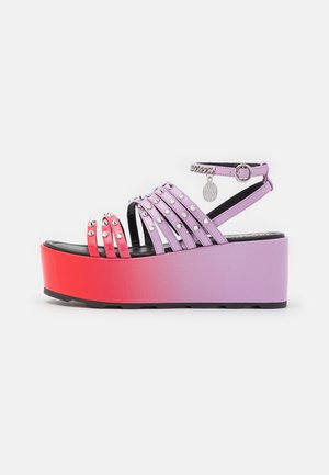 Platformsandal med gradient rød til lilla sål, lilla og røde piggede remme, ankelspænde og hængende rundt vedhæng.