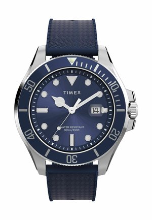 Montre Timex avec un bracelet en caoutchouc texturé bleu marine, boîtier en acier inoxydable, cadran bleu, aiguilles en argent et index horaires blancs. Étanche jusqu'à 100 m.