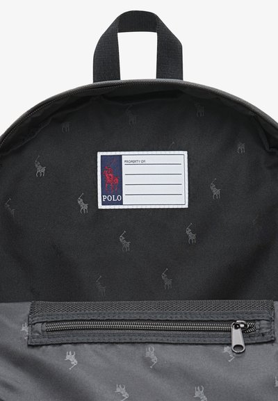 Svart tygryggsäcksinteriör med ett upprepat mönster av polo-spelare, dragkedjeficka och ett etikettområde märkt "PROPERTY OF" med en emblem.