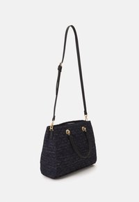Marineblauwe gestructureerde handtas met goudkleurige accenten, dubbele handvatten en een afneembare schouderriem, met een gestructureerde vorm en een geweven ontwerp.