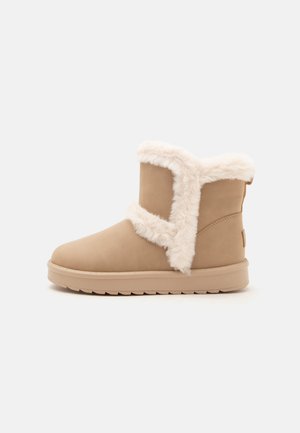 Hellbrauner Winter-Stiefeletten mit weichem weißem Fellbesatz und flacher Gummisohle, Seitenansicht isoliert auf hellem Hintergrund.
