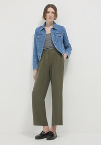 Giacca di denim blu chiaro, top grigio aderente, pantaloni larghi verde oliva e mocassini neri. Design semplice con tasche frontali e texture liscia.