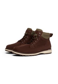 Stivaletti alla caviglia in suede marrone con collare in tessuto verde oliva, suola in gomma beige e occhielli metallici, caratterizzati da un design minimalista e dettaglio del logo.
