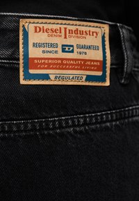 Δερμάτινο λογότυπο σε μαύρο τζιν με την επωνυμία «Diesel Industry Denim Division» και κείμενο σχετικά με την ποιότητα και την εγγραφή από το 1978.