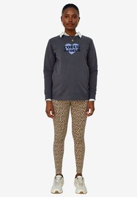 Gray sweatshirt with multicolor heart graphic, paired with leopard-print leggings and white sneakers. Features a layered collar look.