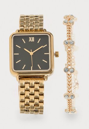 Montre en or avec un cadran carré noir et des index dorés à côté d'un bracelet en or avec des pierres rondes blanches et grises marbrées.