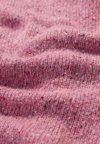 Teksturowana dzianina w różnych odcieniach różu z kropeczkami czerwieni i bieli, prezentująca miękki, przytulny wygląd oraz prążkowany wzór.