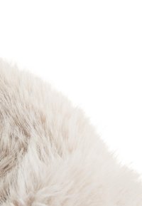 Makro záber na jemnú, svetlo béžovú srsť s jemnými, hustými chlpmi na bielom pozadí.