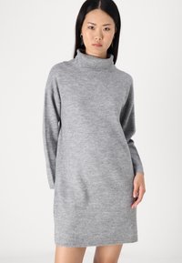 Vestido gris de cuello alto, confeccionado en material suave, con mangas largas y un corte relajado, adornado con un borde y detalle en el cuello acanalado.