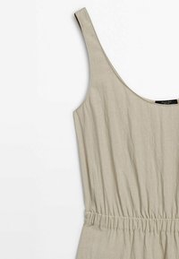 Robe sans manches beige clair avec encolure ronde et taille froncée, confectionnée dans un tissu froissé, présentant une texture lisse et un design minimaliste.