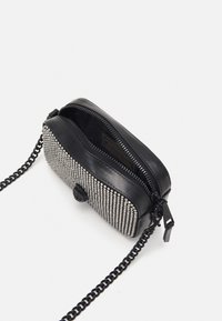 Musta nahkalaukku, jossa on metalliset strassit edessä. Varustettu vetoketjulla, teksturoidulla pinnalla ja ketjuhihnalla. Kompakti muotoilu.