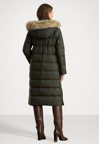 Dlhý, tmavozelený puffrovaný kabát s kapucňou a odnímateľným umelým kožúškom. Textúrovaná tkanina, prešívaný dizajn a postranné rozparky pre voľnosť pohybu.
