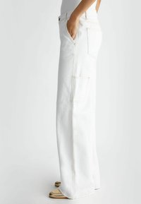 Białe jeansy o szerokich nogawkach z denimu, z wysokim stanem, bocznymi kieszeniami i kontrastowym żółtym przeszyciem. Gładka tekstura, minimalistyczny design.