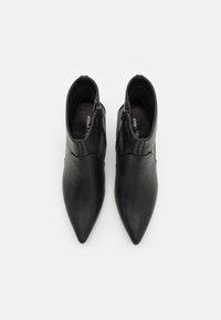 Schwarze Lederstiefeletten mit spitzem Zehenbereich, ausgestattet mit einem seitlichen Reißverschluss und glatter Textur. Minimalistisches Design mit dezentem Steppdetail.