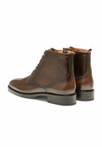 Bottes chelsea en cuir marron à la finition lisse, avec six paires d'œillets, un bout rond et un talon empilé. Doublées de cuir beige.