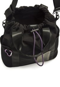 Borsa di tessuto nera con parte superiore arricciata, spallacci regolabili, cordoncino viola e moschettone argentato. Presenta una base testurizzata per la durata.