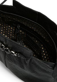 Sac à main en cuir noir ouvert, montrant un intérieur en tissu noir avec des pois dorés, une poche zippée et un détail en chaîne argentée à l'extérieur.