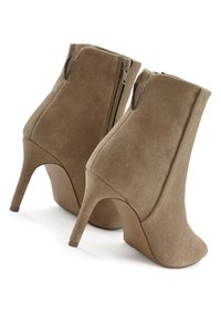 Hnědé semišové kotníkové boty s špičatou špičkou, vysokým stiletto podpatkem a bočním zipem. Hladká textura a přiléhavý design zvýrazňují siluetu.