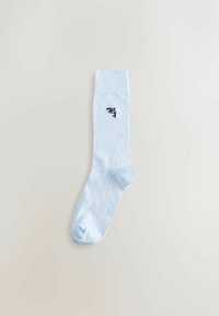 Šviesiai mėlynos medvilninės kojinės su raišteliu ir juodu banginio silueto siuvinėtu logotipu šone. Lygus paviršius ir standartinis ilgio modelis.