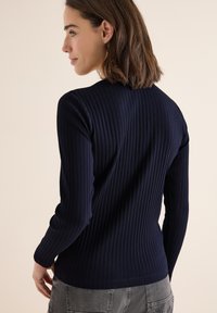 Navyfarbener, geripptes Langarmtop mit taillierter Passform, vertikalen Streifen und rundem Ausschnitt, aus weichem, dehnbarem Stoff gefertigt.