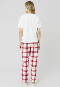 T-shirt en coton blanc associé à un pantalon large à carreaux rouge et blanc. Les pantalons présentent une texture douce et une coupe droite.