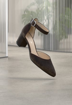 Brauner Wildlederpumps mit Knöchelriemen, spitzer Zehenpartie und Blockabsatz. Die Sohle ist glatt und das Innere cremefarben.