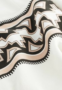 Mönstrad textil med en vågig design i svart och beige mot en vit bakgrund, med tydliga kontrasterande kanter och en slät yta.