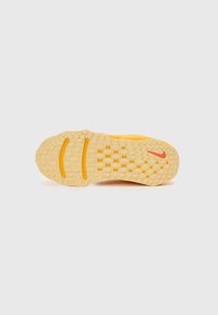 Nike batų padas iš minkštos geltonos guminės medžiagos su tekstūruotu sukibimu. Yra raudonas logotipas, grioveliai traukai ir sustiprintos vietos ilgaamžiškumui.