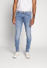 Ljusblå tajta jeans av denim, med ett standard midjeband och knappstängning, fem fickor och en lätt blekt finish.