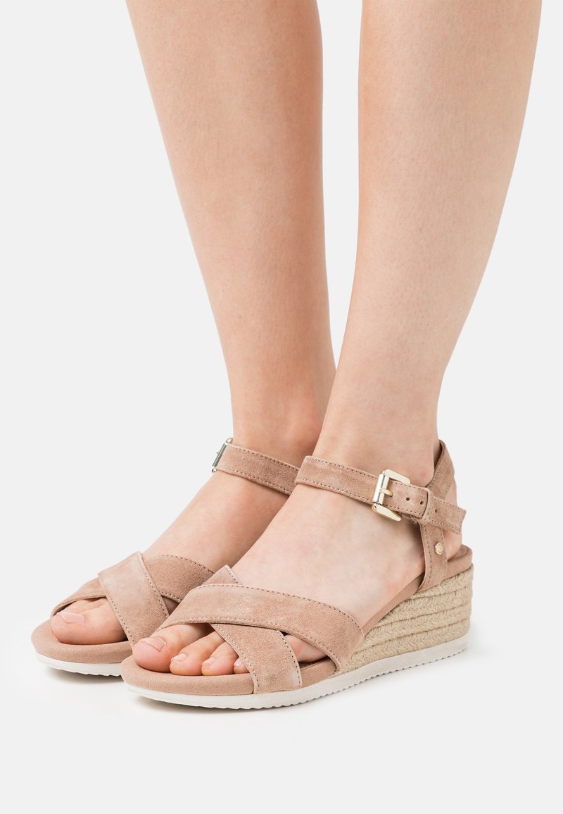 Sandali con zeppa in suede beige, dotati di cinturini incrociati, fibbia alla caviglia e suola intermedia in corda intrecciata. Superficie liscia con una consistenza morbida.