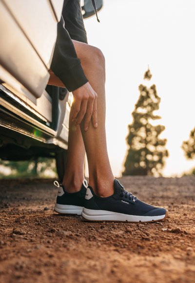 Námořnické lehké sneakers s texturovaným svrškem a bílou podrážkou. Mezi funkce patří šněrování, poutko a hladký gumový kryt špičky.