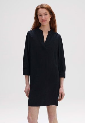 Robe noire en tissu texturé, avec un décolleté en V, des manches trois-quarts et une coupe ample, atteignant la longueur mi-cuisse.