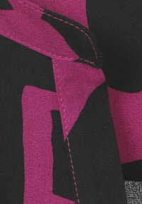 Zwarte stof met grote, gedurfde roze geometrische patronen. Bevat zichtbare stiksels in het roze. Getextureerd katoenmateriaal met een matte afwerking.