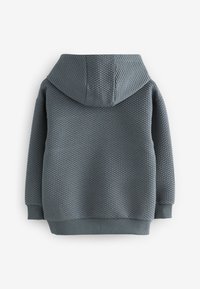 Grå tekstureret hættetrøje med et diamantmønster, der har hætte og ribbet kanter ved ærmer og bund. Bagfra ses dens hyggelige design.