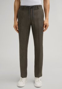 Pantalons légers texturés de couleur brun foncé avec taille à cordon et coupe droite, associés à des baskets blanches.