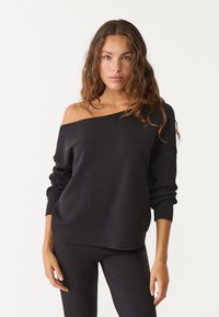 Schwarzer Sweatshirt mit schulterfreier Form aus weichem Stoff, mit lockerer Passform und langen Ärmeln. Glatte Textur mit gerippten Bündchen.