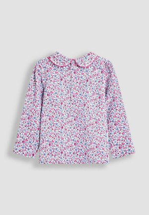 Bluse med lange ærmer har en hvid baggrund med et blomster mønster i pink og blå. Rund krave med knaplukning bagpå.